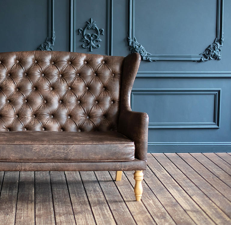 Brown leather sofa in front of blue wall.