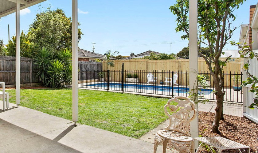 Backyard with pool and wrought iron chair.