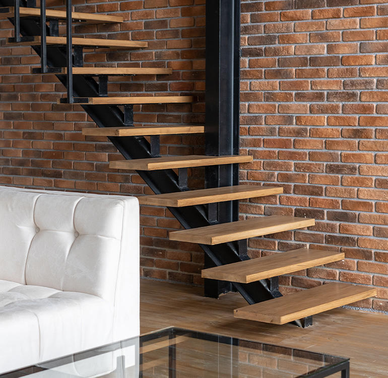 Modern wooden staircase with white sofa and glass coffee table.