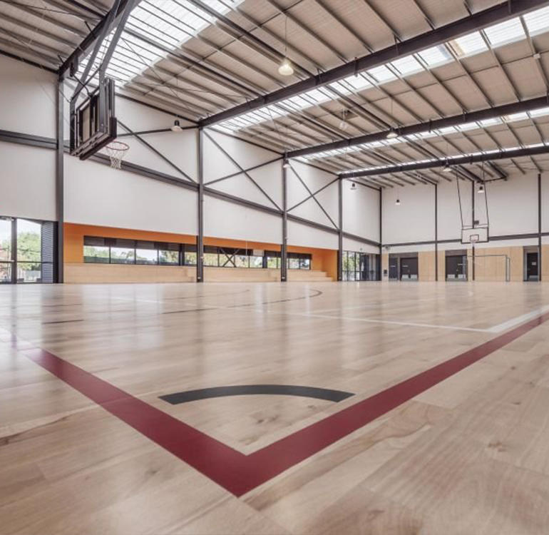 Inside basketball stadium with polished wooden floor.