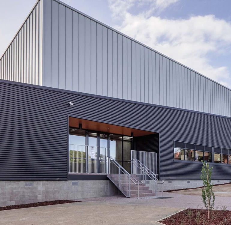 Exterior of gymnasium with grey corrugated siding.