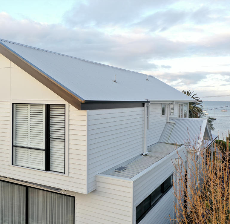 White weatherboard house 2 storey extension.